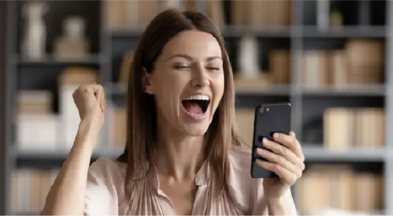 Mujer celebrando con celular en mano